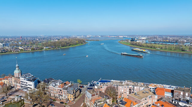 Aerial view of the historic Groothoofds Gate and the junction of three rivers with cargo ships and traditional rooftops under a clear blue sky in Dordrecht, Zuid-Holland, Netherlands.