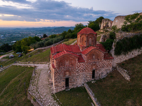 Aerial view of Holy Trinity Church within the Berat Castle walls featuring red tiled roofs and stone masonry at sunset in Berat, Qarku i Beratit, Albania.