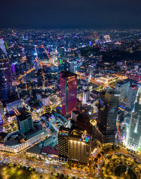 Night aerial view of Ho Chi Minh City skyline with illuminated skyscrapers, busy streets, and vibrant urban lights in Vietnam's financial district.