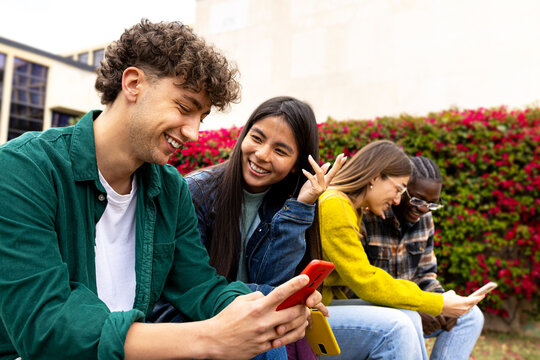 University students sharing funny content on mobile phone outdoors