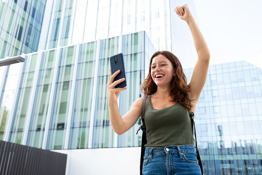 Woman celebrating good news on mobile phone in city