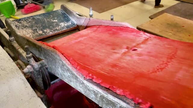 Red Noodle Dough Sheet Coming Out of Traditional Press Machine in Mie Habang Workshop South Kalimantan Indonesia