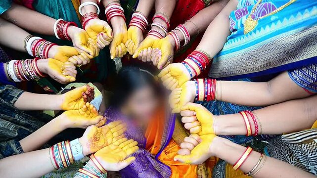 Close-up footage of a traditional Indian Haldi ceremony where family members and friends apply turmeric paste to the bride before marriage. The pre-wedding ritual symbolizes purification, blessings.