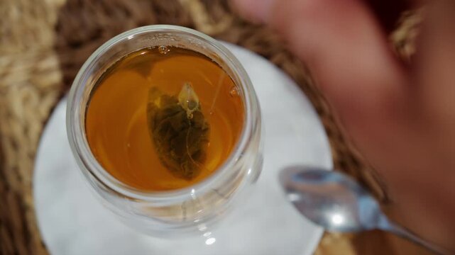 Close up of a tea bag steeping in hot water inside a transparent glass cup