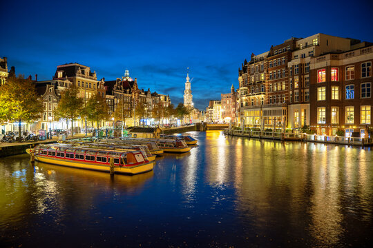Canals in Amsterdam, Netherlands with Munttoren, Canal Boats and architecture at night in Blue Hour
