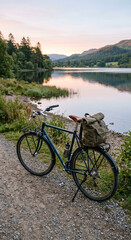 Fototapeta premium Bicycles by a lakeside path at dusk as bicycles by lake detail for summer cycling with calm water and mountain view in summer light