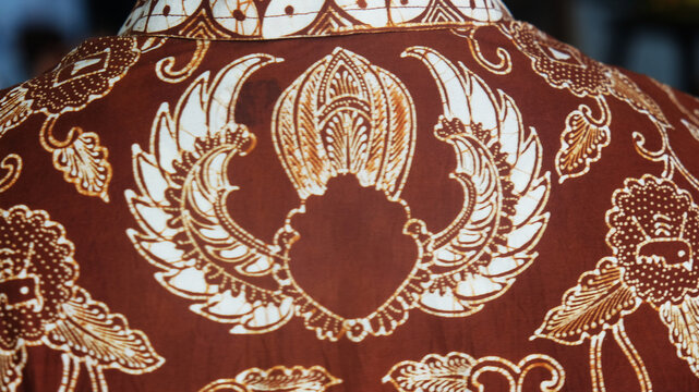 Close up back view of traditional Indonesian brown batik fabric shirt with garuda wing pattern.