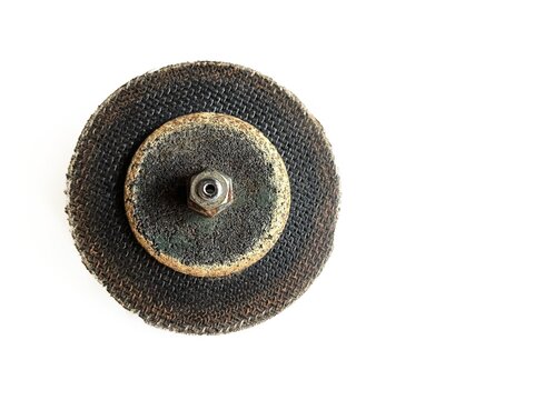 Used grinding abrasive disc wheel with nut, isolated on white background. Old worn metal cutting or sanding wheel tool for industrial workshop, mechanical hardware, and construction mockup.