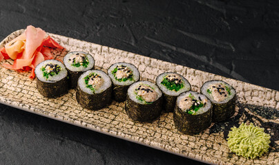 Delicious maki sushi feature fresh green seaweed salad filling. Gourmet Japanese food sits on decorated plate with wasabi. © AntAlexStudio