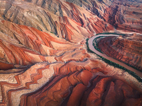Aerial view of the winding San Juan River flowing past the unique zig-zag geological formations of Raplee Ridge near Mexican Hat, Utah, United States.