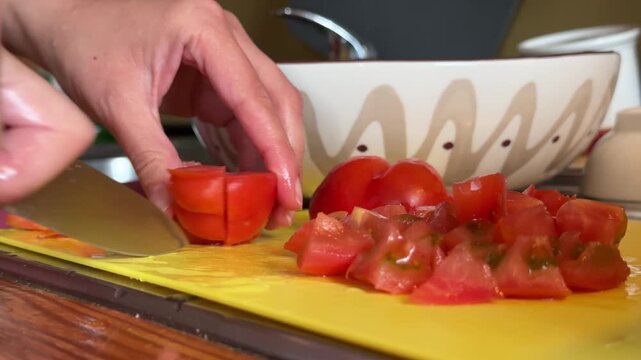 Close-Up Hands Cutting Fresh Tomatoes On Yellow Cutting Board In Home Kitchen Preparation	