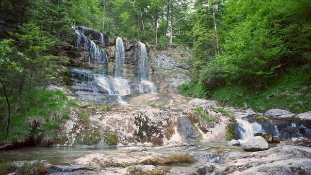 Weissbach waterfall in Schneizlreuth, Germany during summer season. Fresh mountain water splashing on rocks in forest in German Alps region. Natural attraction and popular travel destination.