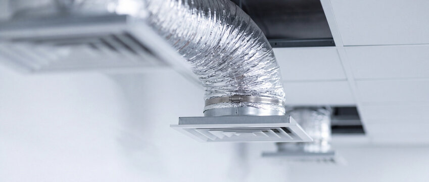 Commercial HVAC ventilation ducts and ceiling air diffusers in modern suspended ceiling interior