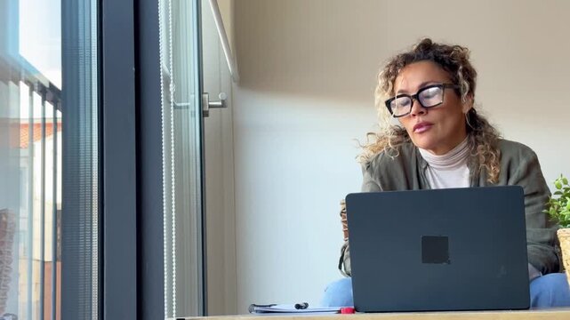 Exhausted woman feeling sleepy, yawning and stretching her neck while working long hours on her computer at home office, showing signs of fatigue, burnout and need for rest