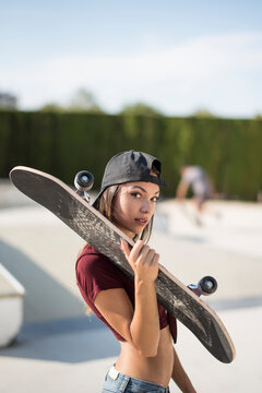 Pretty skater woman with skate in sunny day looking at camera