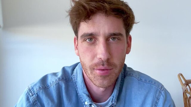 Handsome caucasian man speaking directly to the camera during an online video call, actively participating in a virtual meeting or having a conversation with a friend from his home office