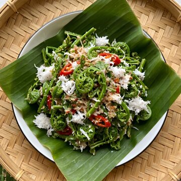 Kerabu Umbut Paku is a traditional Negeri Sembilan fern shoot salad tossed with grated coconut and spicy chili dressing, offering fresh flavors and rustic heritage appeal.