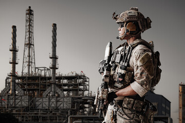 Obraz premium Soldier stands at Gas Oil Refinery industrial facility in a military Energy operation security.