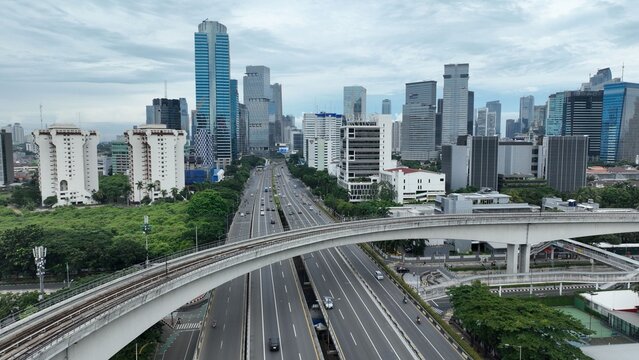 Aerial view of modern skyscrapers and a multi-lane highway with an elevated rail track in West Kuningan district Mampang Prapatan, Jakarta, Indonesia.