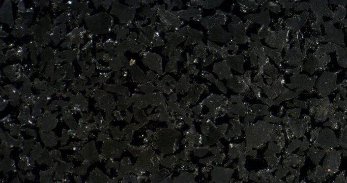 Top‑down close‑up of coarse black recycled rubber granules