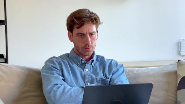 Focused young man sitting on the sofa working or studying on his laptop, displaying a range of emotions from concentration and thoughtfulness to stress and finally smiling