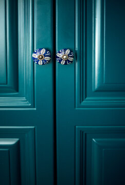 Blue cabinet doors with decorative ceramic knobs featuring floral patterns, showcasing a modern design in a stylish interior setting