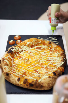 emplatado de pizza artesanal reci&eacute;n horneada con queso fundido y salsa