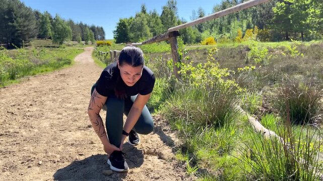 A female runner has pain in der ankles while jogging on a dirt road