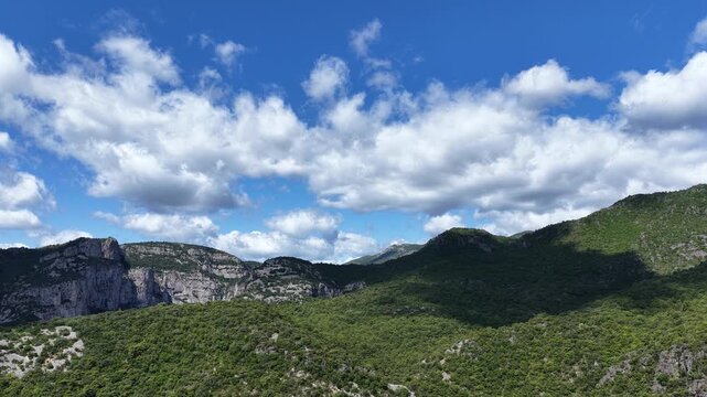Scenic aerial view of rolling green hills and rocky ridges in a mountainous landscape.
