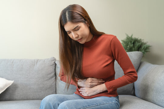 asian young woman intolerance hand in stomach ache, suffer from food poisoning, abdominal pain and colon problem