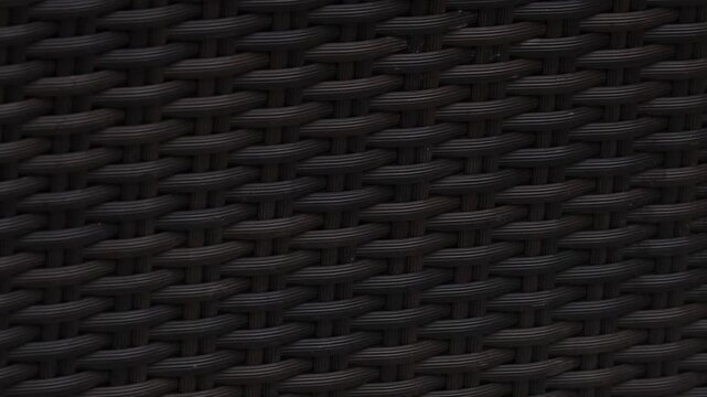 4K close-up video of a woven chair surface showing intricate wicker patterns and natural texture details. The camera focuses on the craftsmanship, material structure, and repeating weave design