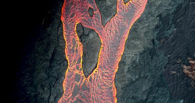 A drone view of glowing molten lava flowing over dark volcanic rock on Hawaii Kilauea Volcano, showing raw heat and texture