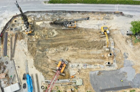 Aerial view of a busy construction site with heavy machinery, drilling rigs, and workers in high-visibility vests on a dirt ground in Bagcilar, Istanbul, Turkiye.