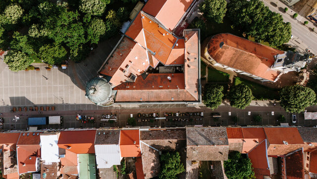 Aerial view of the historic city center featuring red-tiled rooftops, a church with a dome, and a paved square with outdoor cafe seating in Sremska Mitrovica, Vojvodina, Serbia.
