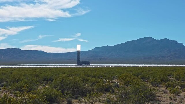 Ivanpah solar tower glowing above Mojave Desert landscape and mountains, Renewable energy video frame with heliostat mirrors bright sunlight and arid scenery