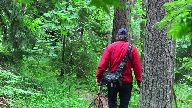 A fisherman went fishing in the forest. Green forest with ribfish and spinen. Summer greenery around