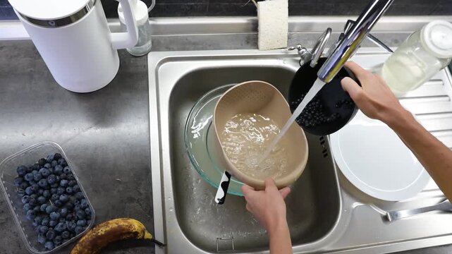 Washing fresh blueberries in kitchen sink with running water before healthy meal preparation video Full HD
