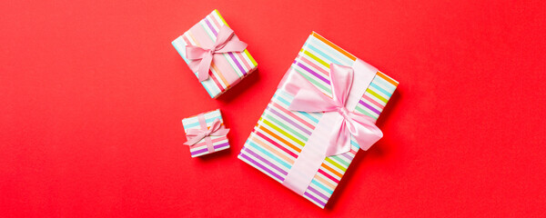 Fototapeta premium Gift box with pink bow for Christmas or New Year day on red background, top view