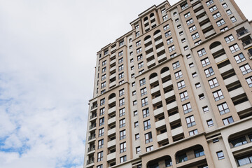 Fototapeta premium Soaring residential tower reaching toward sky with layered balconies and arched openings, evoking ambition, height and metropolitan energy for lifestyle and development use