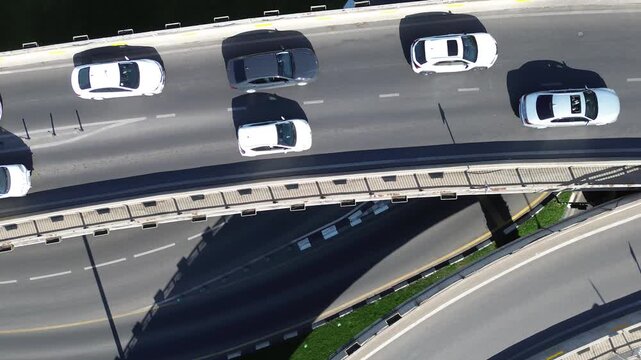 Original unedited 4K drone bird's eye footage ascending above a highway roundabout with bridge loop and circular traffic in Tbilisi, Georgia at golden hour. No color grading applied.