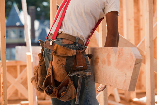 Mid section view of a carpenter carrying a wooden rafter
