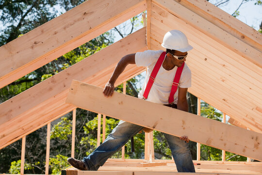Carpenter carrying a wooden rafter