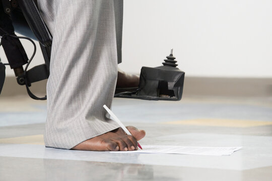 Businessman with Cerebral Palsy signing a document with his foot