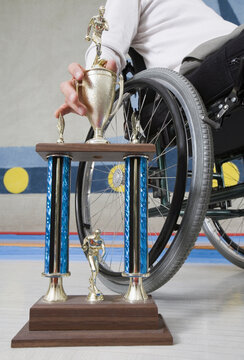 Mid section view of a disabled man sitting in a wheelchair and holding a trophy