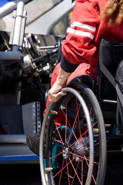 Woman entering driver's seat of racing car from wheelchair, close-up