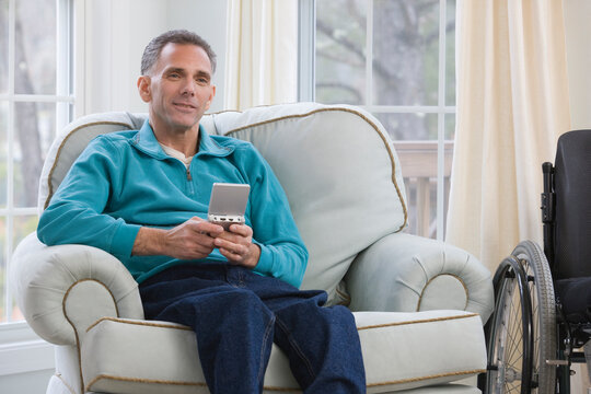 Man sitting in a wheelchair and holding a personal data assistant