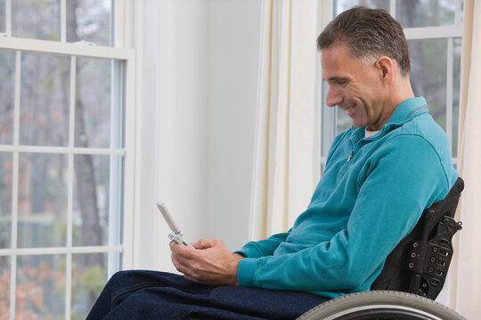 Man sitting in a wheelchair and using a personal data assistant