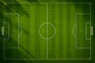 Obraz premium Aerial view of a green soccer field with white line markings and dramatic lighting