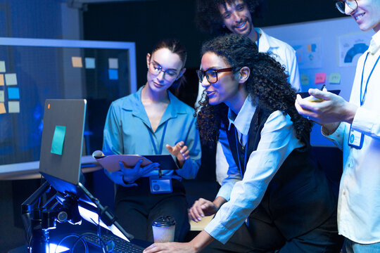Diverse software engineer team check data on monitor. Tech startup female developer lead group to inspect computer program code, web design, and network infrastructure system in office