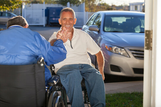 Man with Friedreich's Ataxia greeting his friend with spinal cord injury